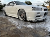 a white nissan gtr is being washed on a brick driveway