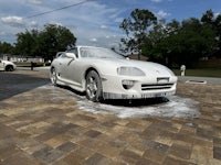 a white sports car sitting on a brick driveway